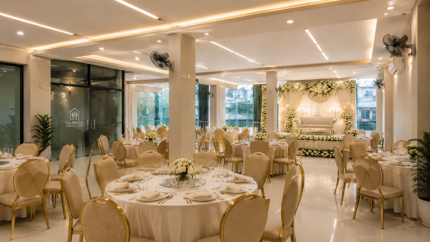 Our Mezban hall arranged with round dining tables and a decorated stage